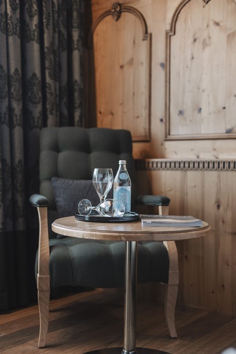 Pictures from Sportalm Armchair beside table with water bottle, glasses and book in wooden room