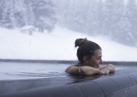 Bilder aus der Sportalm Frau entspannt im beheizten Außenpool bei Schneefall