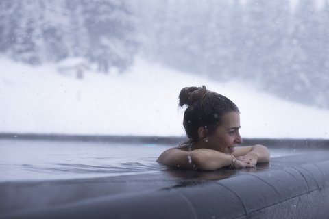 Bilder aus der Sportalm Frau entspannt im beheizten Außenpool bei Schneefall