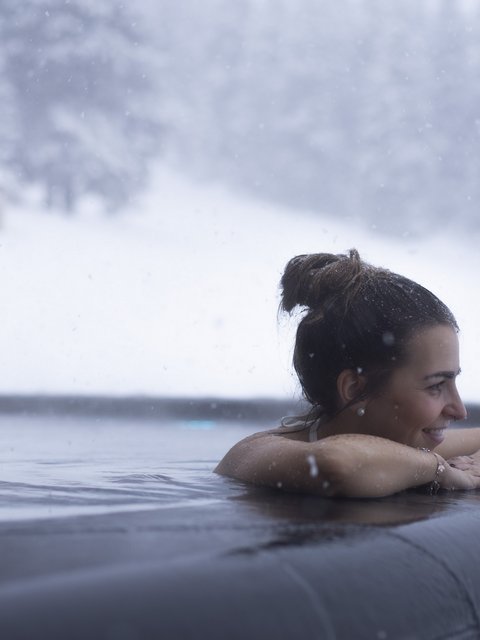 Bilder aus der Sportalm Frau entspannt im beheizten Außenpool bei Schneefall