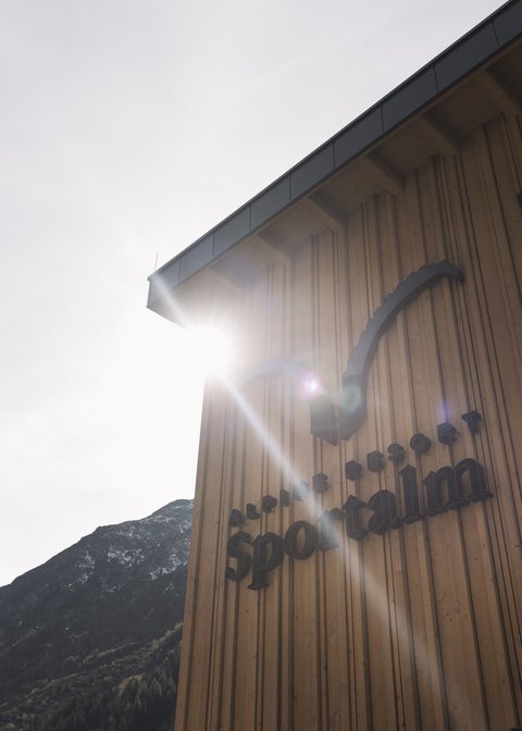 Bilder aus der Sportalm Gebäudewand mit Alpine Resort Sportalm Schriftzug im Sonnenlicht