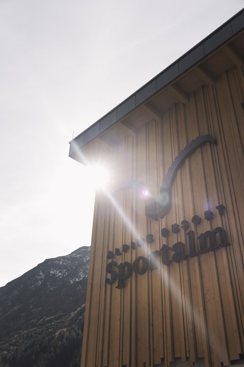 Bilder aus der Sportalm Gebäudewand mit Alpine Resort Sportalm Schriftzug im Sonnenlicht