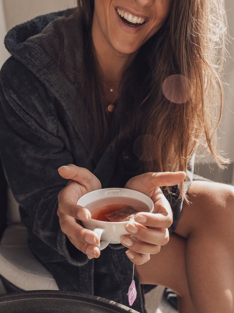Pictures from Sportalm Woman in bathrobe holding a cup of tea smiling