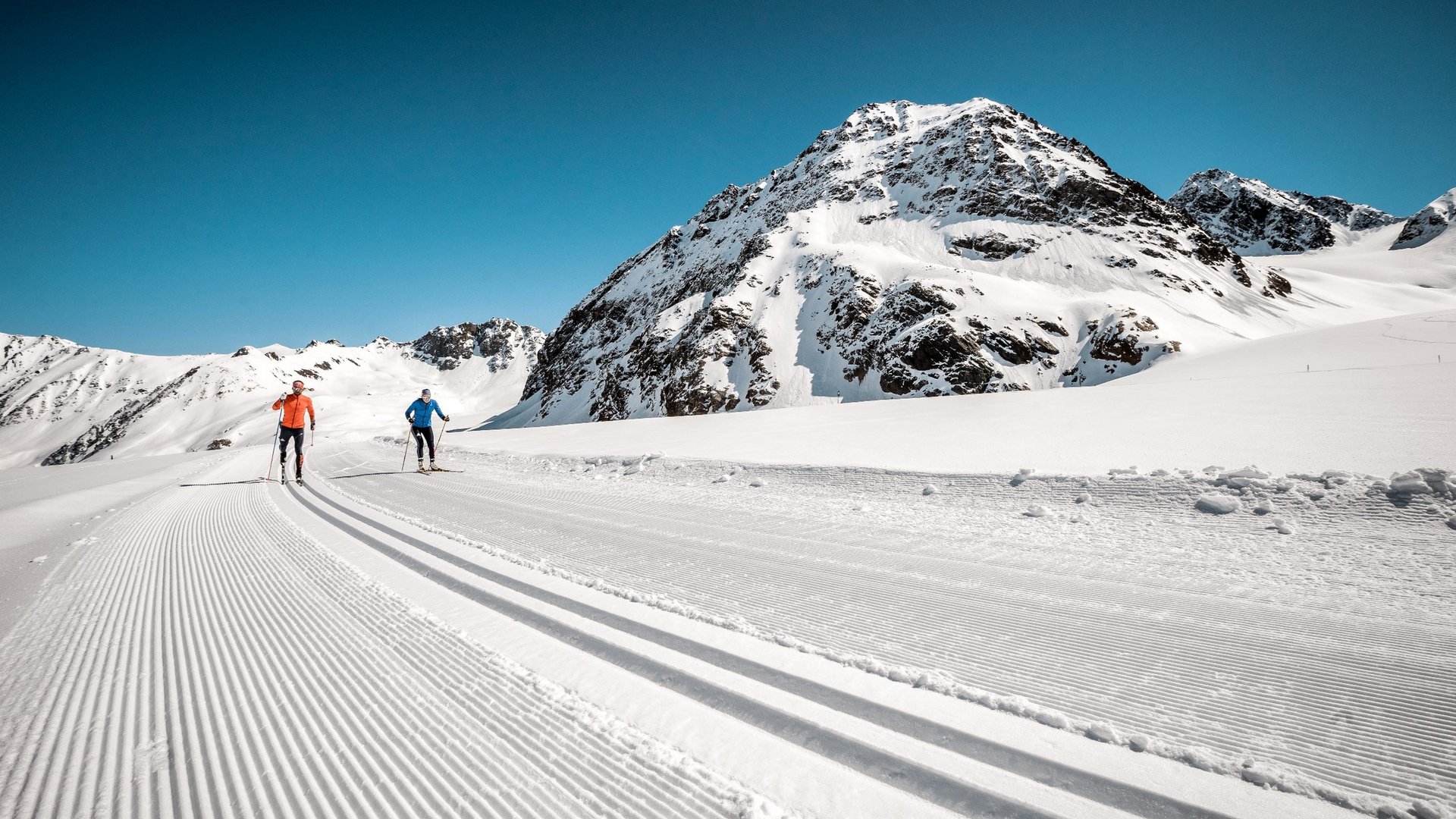 Cross-country skiing in Pitztal Two cross-country skiers on groomed trail in snowy mountain scenery