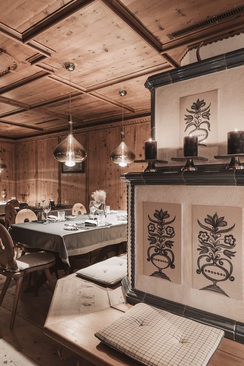 Bilder aus der Sportalm Gemütlicher Holzraum mit dekorativem Ofen und gedeckten Tischen