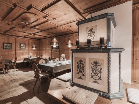 Our restaurant in Pitztal Cozy wooden room with decorative stove and set dining tables
