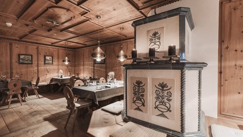 Bilder aus der Sportalm Gemütlicher Holzraum mit dekorativem Ofen und gedeckten Tischen