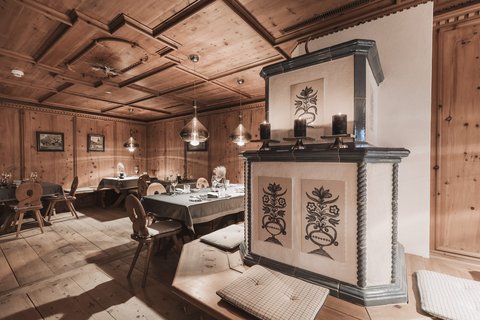 Bilder aus der Sportalm Gemütlicher Holzraum mit dekorativem Ofen und gedeckten Tischen