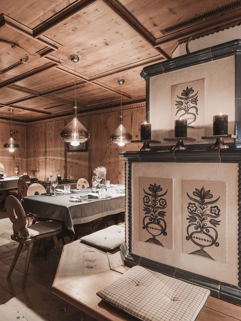 Bilder aus der Sportalm Gemütlicher Holzraum mit dekorativem Ofen und gedeckten Tischen