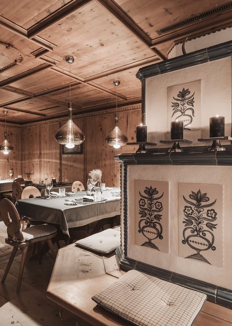 Bilder aus der Sportalm Gemütlicher Holzraum mit dekorativem Ofen und gedeckten Tischen