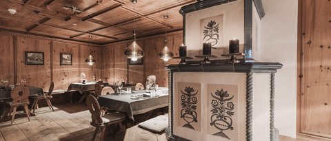Bilder aus der Sportalm Gemütlicher Holzraum mit dekorativem Ofen und gedeckten Tischen