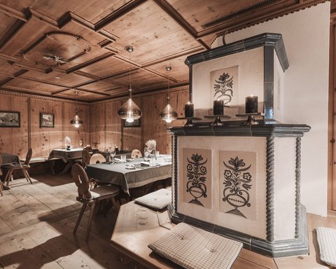 Bilder aus der Sportalm Gemütlicher Holzraum mit dekorativem Ofen und gedeckten Tischen
