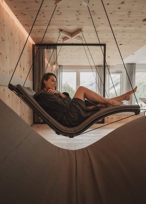 Pictures from Sportalm Woman relaxing on a hanging lounge in a modern room with wooden paneling