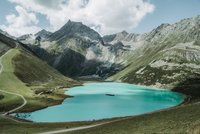 Clear alpine lake surrounded by tall mountains with hiking trails