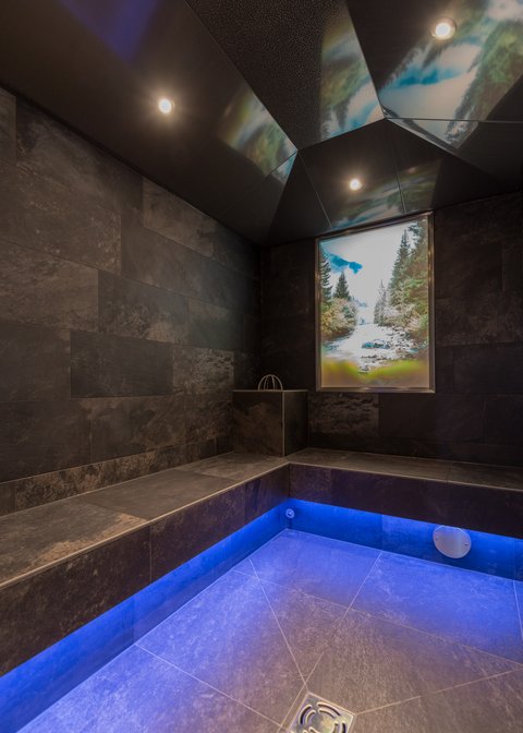 Urlaub im Pitztal? Unterkunft mit Pep! Moderner Wellnessraum mit dunklen Fliesen und blau beleuchtetem Boden