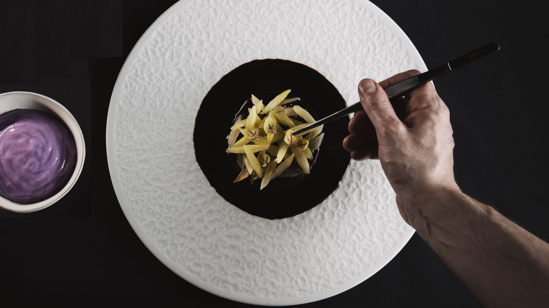 Our restaurant in Pitztal Hand plating yellow vegetable dish with sauce on white textured plate