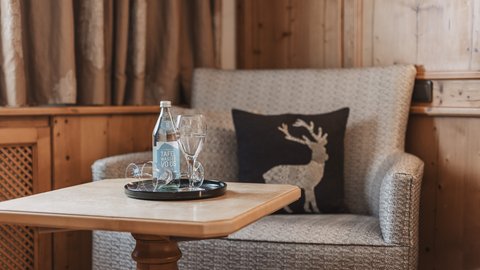 Pictures from Sportalm Cozy seating area with water bottle, glasses, and deer cushion on wooden paneling