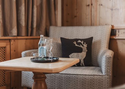 Pictures from Sportalm Cozy seating area with water bottle, glasses, and deer cushion on wooden paneling