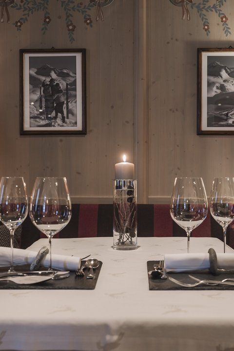 Bilder aus der Sportalm Gemütlicher Esstisch mit Kerze, zwei Gedecken und Lampen im Holzraum