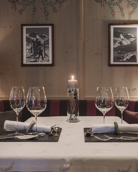 Bilder aus der Sportalm Gemütlicher Esstisch mit Kerze, zwei Gedecken und Lampen im Holzraum