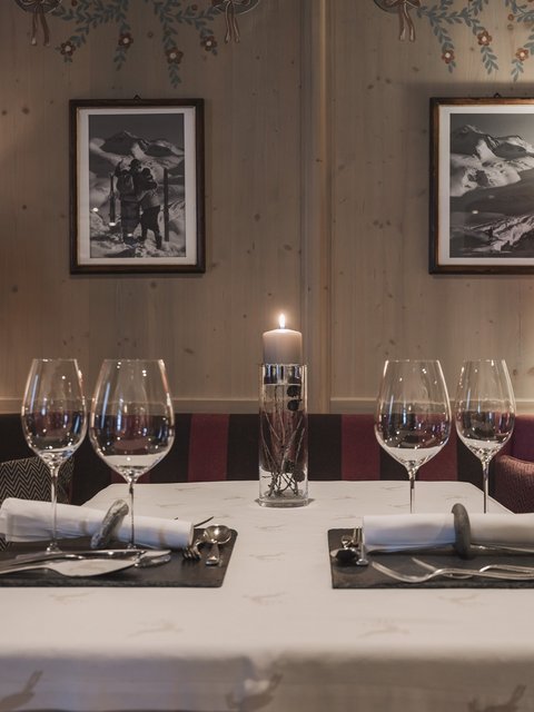 Bilder aus der Sportalm Gemütlicher Esstisch mit Kerze, zwei Gedecken und Lampen im Holzraum