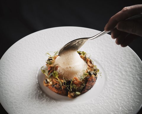 Bilder aus der Sportalm Fein angerichtetes Gericht mit Schaum auf weißem Teller vor schwarzem Hintergrund