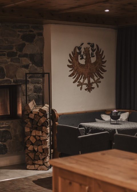 Bilder aus der Sportalm Gemütlicher Raum mit Steinofen, Holzstapel und verzierten Wänden