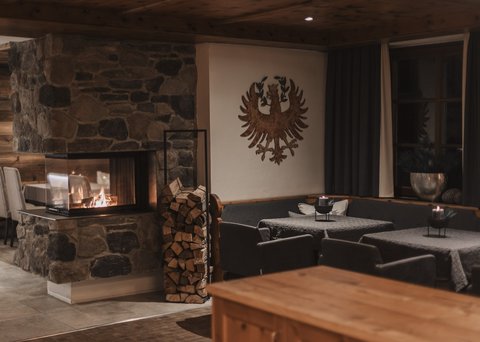 Bilder aus der Sportalm Gemütlicher Raum mit Steinofen, Holzstapel und verzierten Wänden