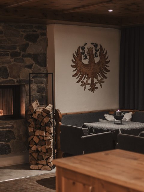 Bilder aus der Sportalm Gemütlicher Raum mit Steinofen, Holzstapel und verzierten Wänden