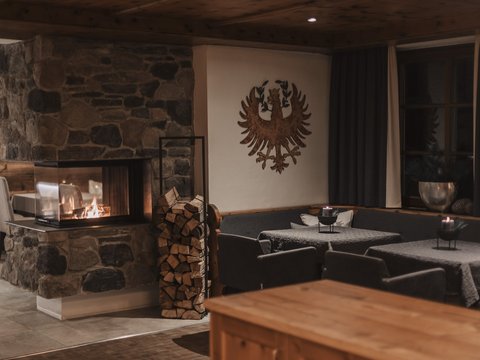 Bilder aus der Sportalm Gemütlicher Raum mit Steinofen, Holzstapel und verzierten Wänden