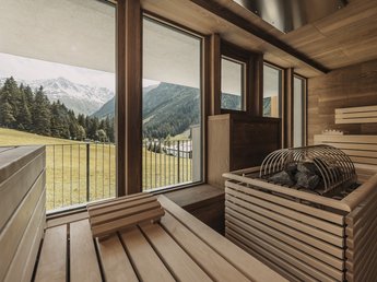 News from Sportalm Wood-paneled sauna with view of mountains and grassy meadow