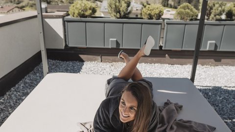Bilder aus der Sportalm Frau liegt auf Terrasse unter Sonnenschutz mit Glas Wein in der Hand