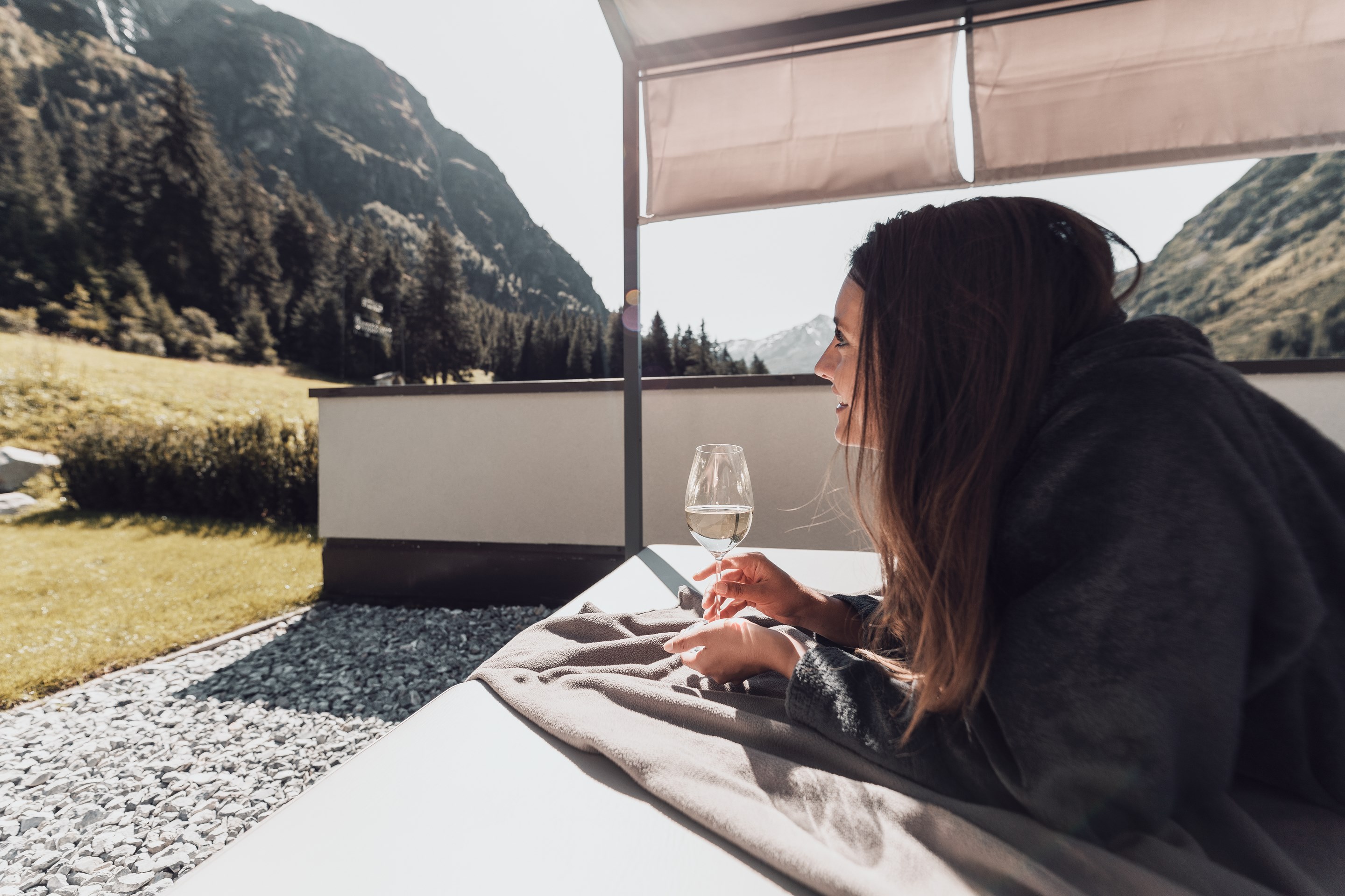 Freude schenken Frau liegt auf Liege mit Glas Weißwein in Berglandschaft